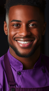 En leende man som bär en lila kockuniform och tittar direkt in i kameran.